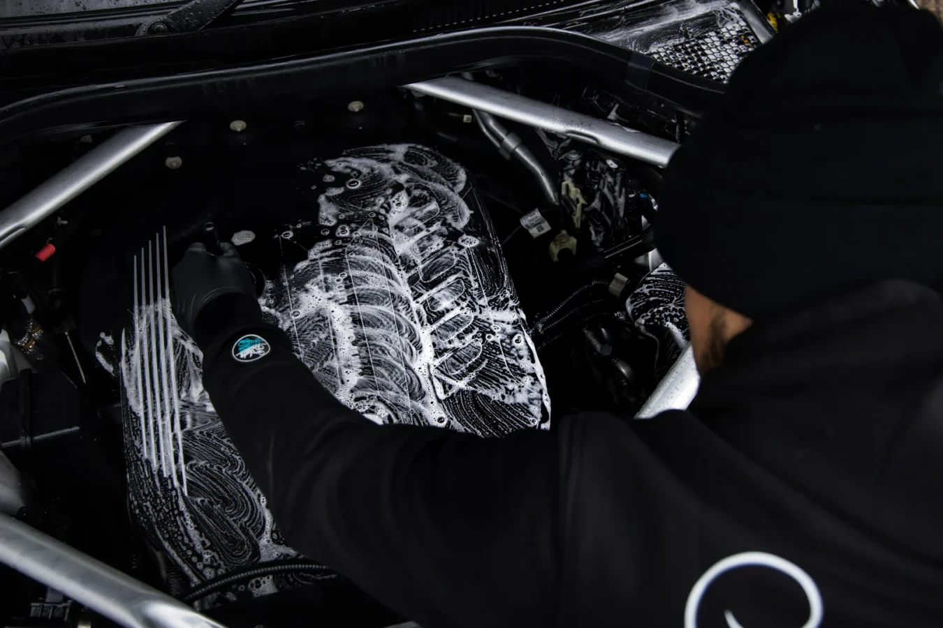 Mechanic cleaning car engine with soapy water.